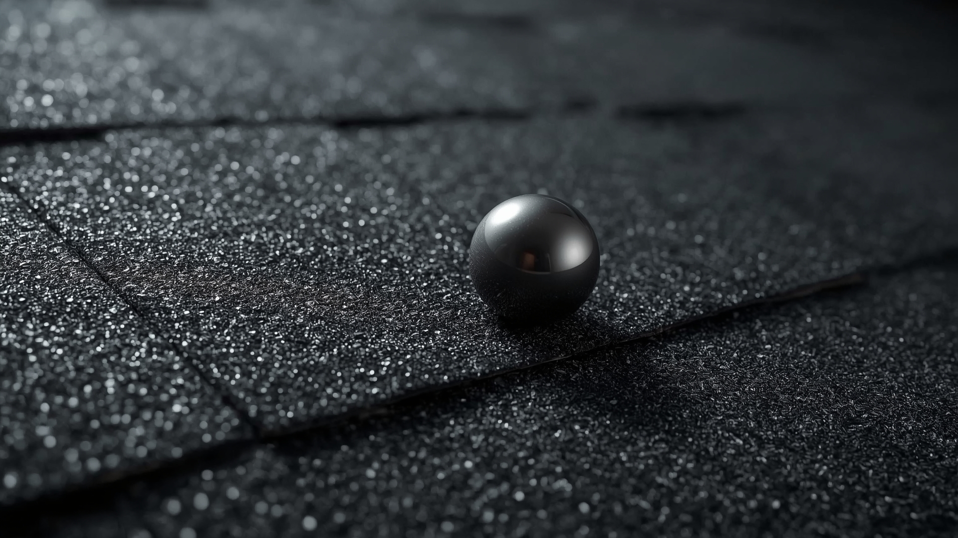Close-up macro view of Class 4 impact resistant asphalt shingle surface texture with steel ball